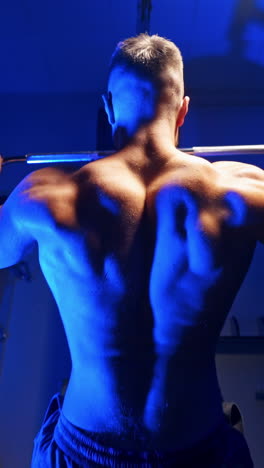 brutal strong athletic men pumping up muscles. doing workout on sport equipment - muscular bodybuilder doing exercises in gym with naked torso. fitness and bodybuilding concept. video from the back. vertical video