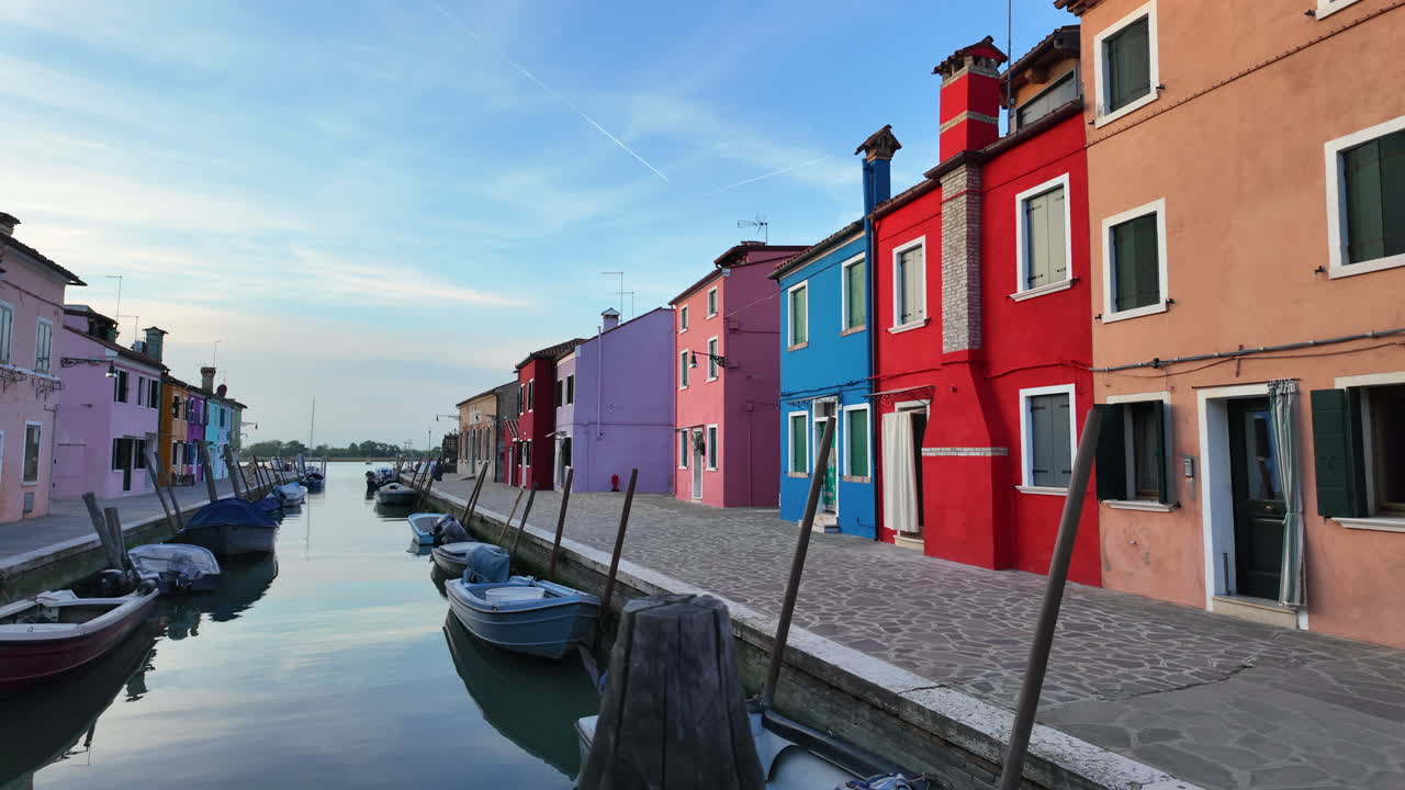 Barcos a los lados de un canal cerca de las coloridas casas de la isla de Burano, Italia