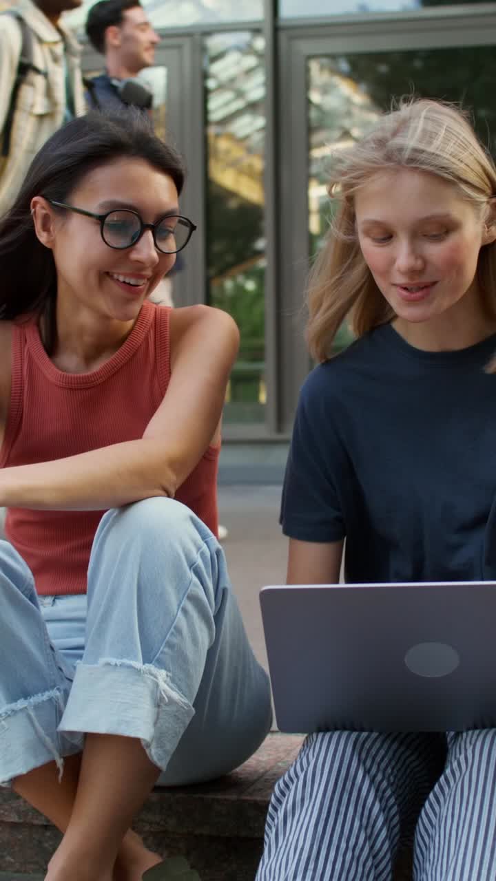 To kvindelige studerende snakker med bærbar computer