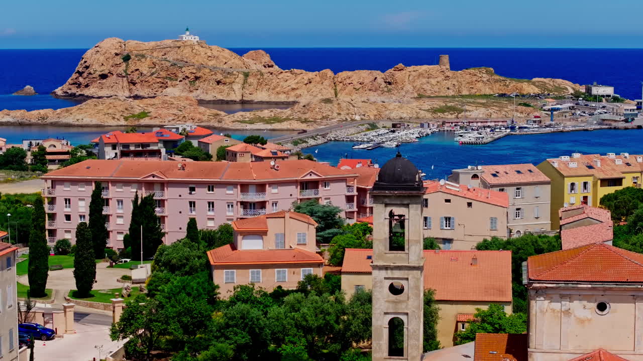 Aerial drone shot over the coastal town Île-Rousse in the Balagne region in Corsica, France. View of the beach and turquoise. Ile de la La Pietra in the