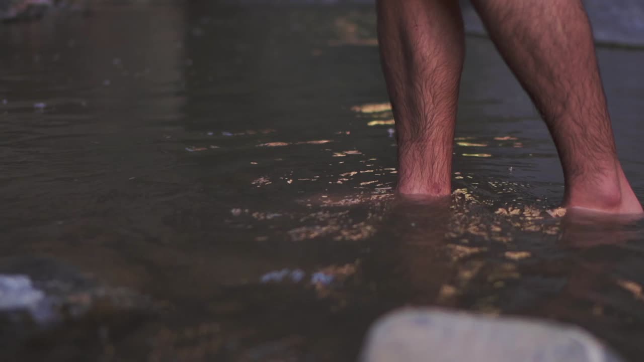 primer plano de las piernas de un hombre caminando por el agua, capturando el movimiento y las salpicaduras