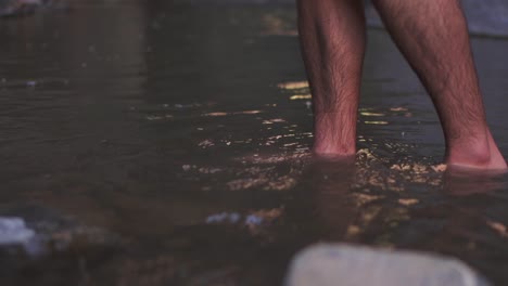 close-up of a man's legs walking through water, capturing the movement and splashes