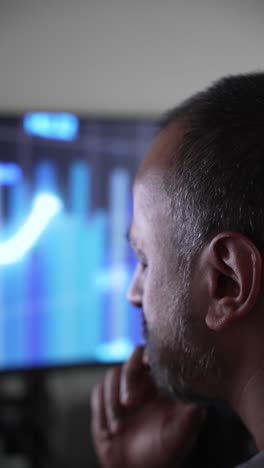 man intently watching screen with hand on chin in focused thought