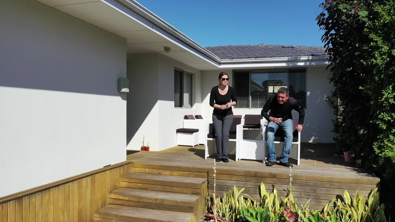 una pareja adulta relajándose en la cubierta de su casa.