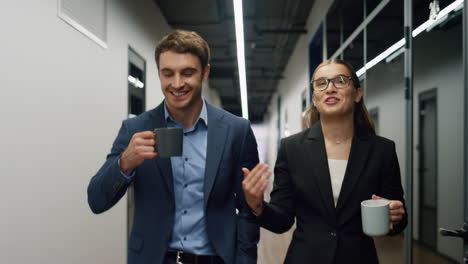 office friends talking break walking hallway. two marketing managers share ideas