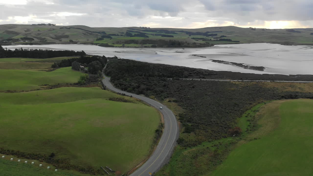 Aerial view of a car driving along a winding road through the scenic landscape of New Zealand's South Island