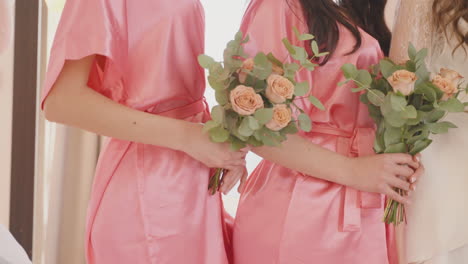 camera focuses on hands of female friends and bride holding bouquets