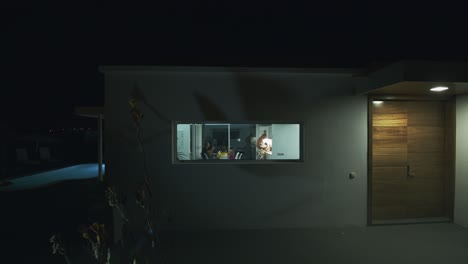 House-outside-view-with-family-being-seen-in-the-window-evening-shot