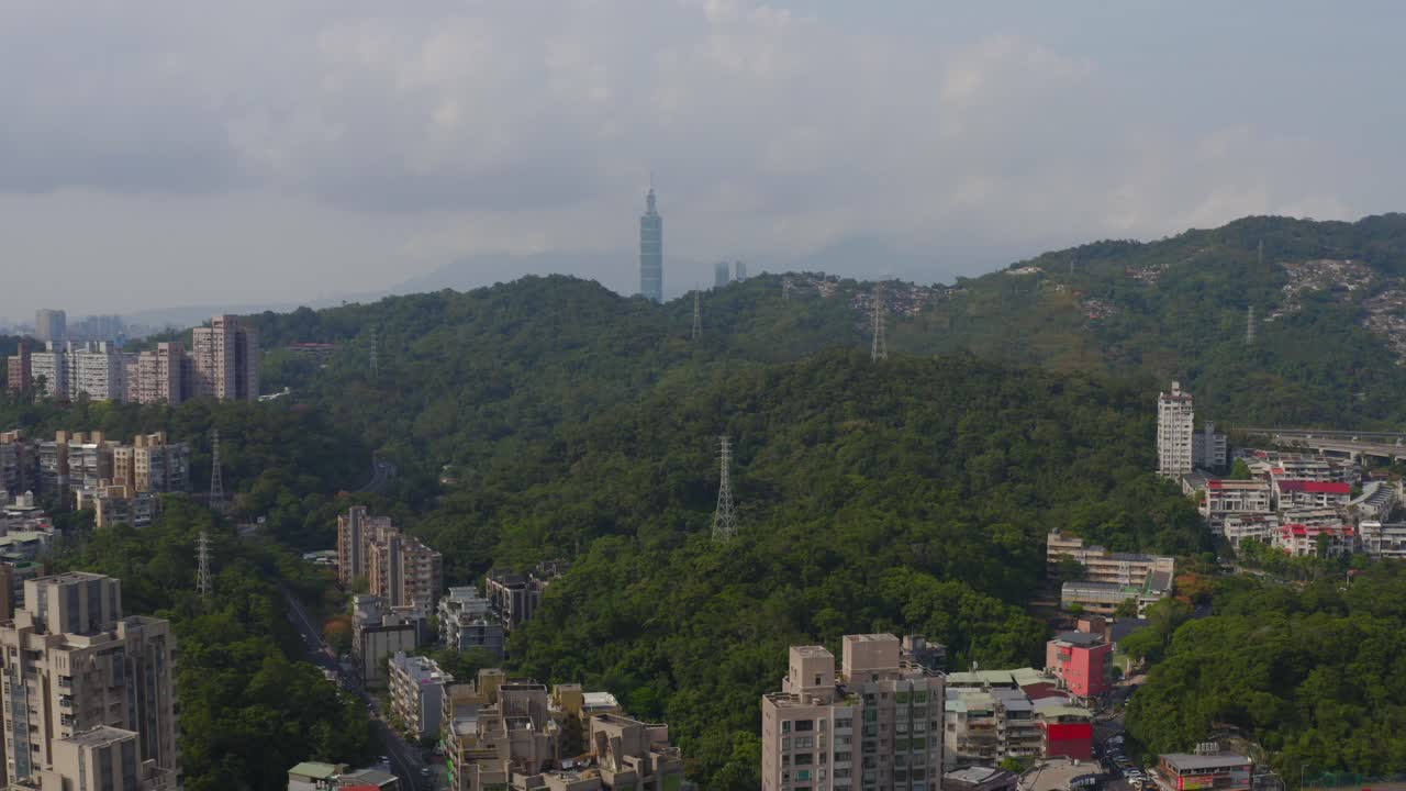 4k Aerial drone footage showing a wide landscape view of a city surrounded by green hills and forests with a tall tower visible on the horizon. perfect for travel, documentary, and cityscape projects