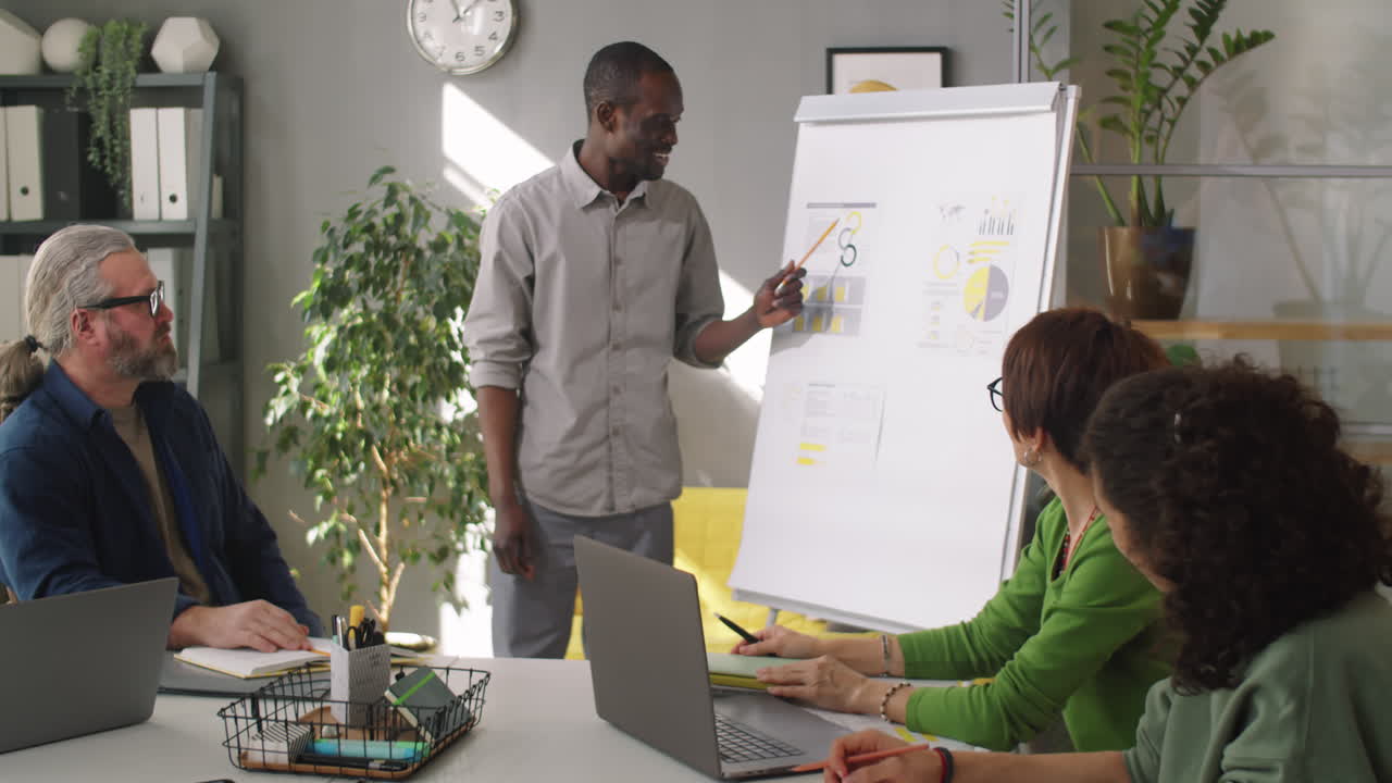 Black Man Giving Business Presentation to Coworkers at Office Meeting