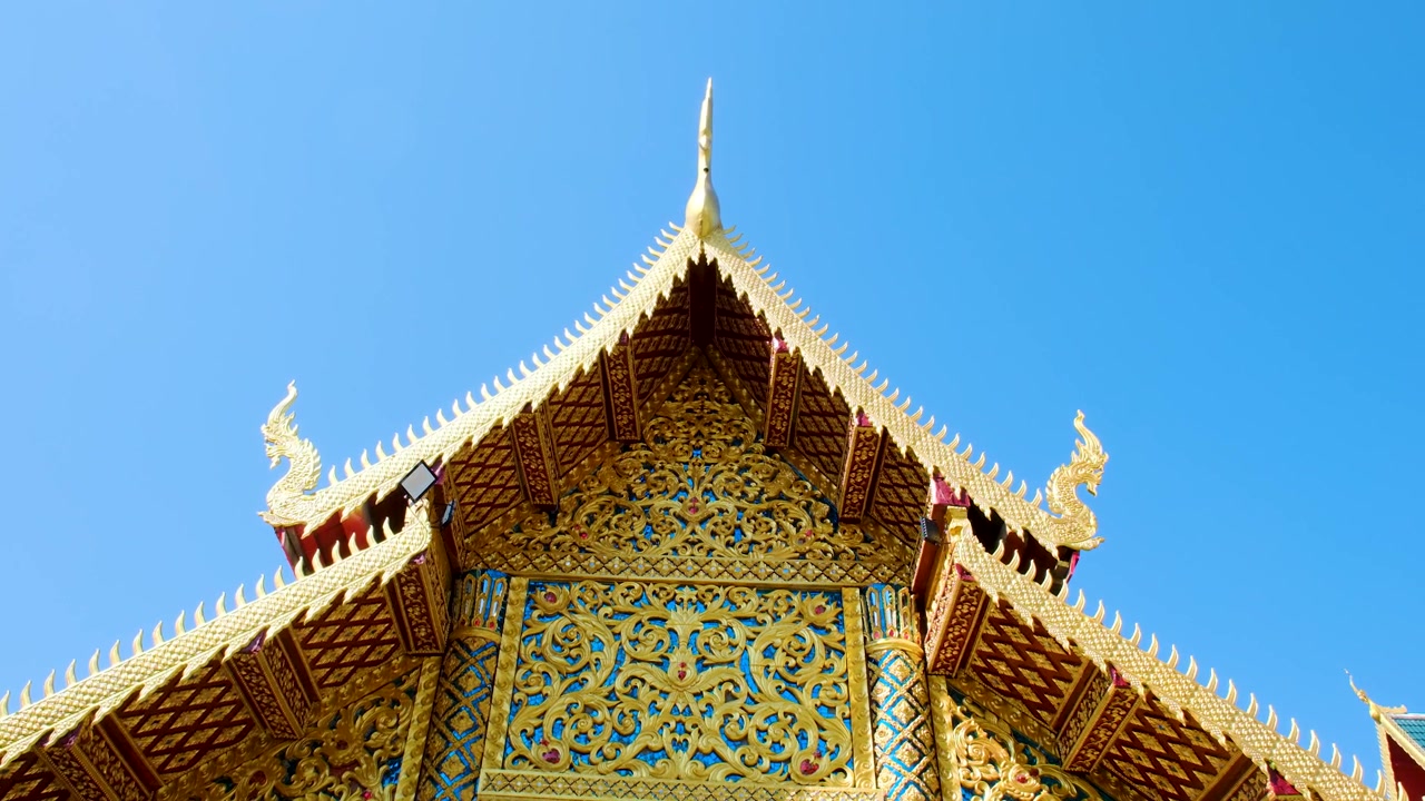 Wat Ou Sai Kham mostra una bellissima architettura tradizionale thailandese con intricati dettagli dorati e un tetto elegante contro un cielo azzurro brillante - Ripresa dal basso