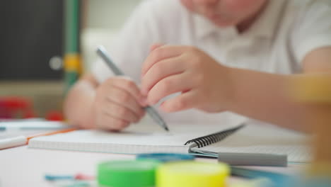 Kleinkindschüler-Zeichnet-Mit-Marker-Im-Schulheft-Am-Tisch