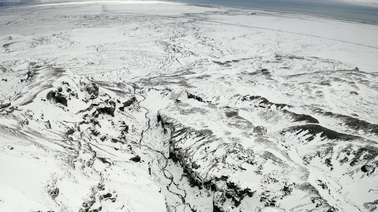 Aerial wide shot forward over frozen wintery landscape in south Iceland. High contrast arctic footage.