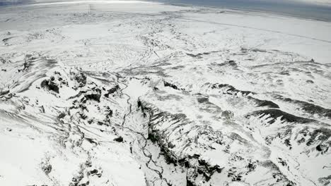 aerial wide shot forward over frozen wintery landscape in south iceland. high contrast arctic footage.