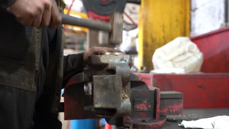 Un-Mecánico-Martillando-Un-Casquillo-De-Latón-En-Una-Carcasa-Sujeta-Firmemente-En-Un-Tornillo-De-Banco-De-Ingeniero