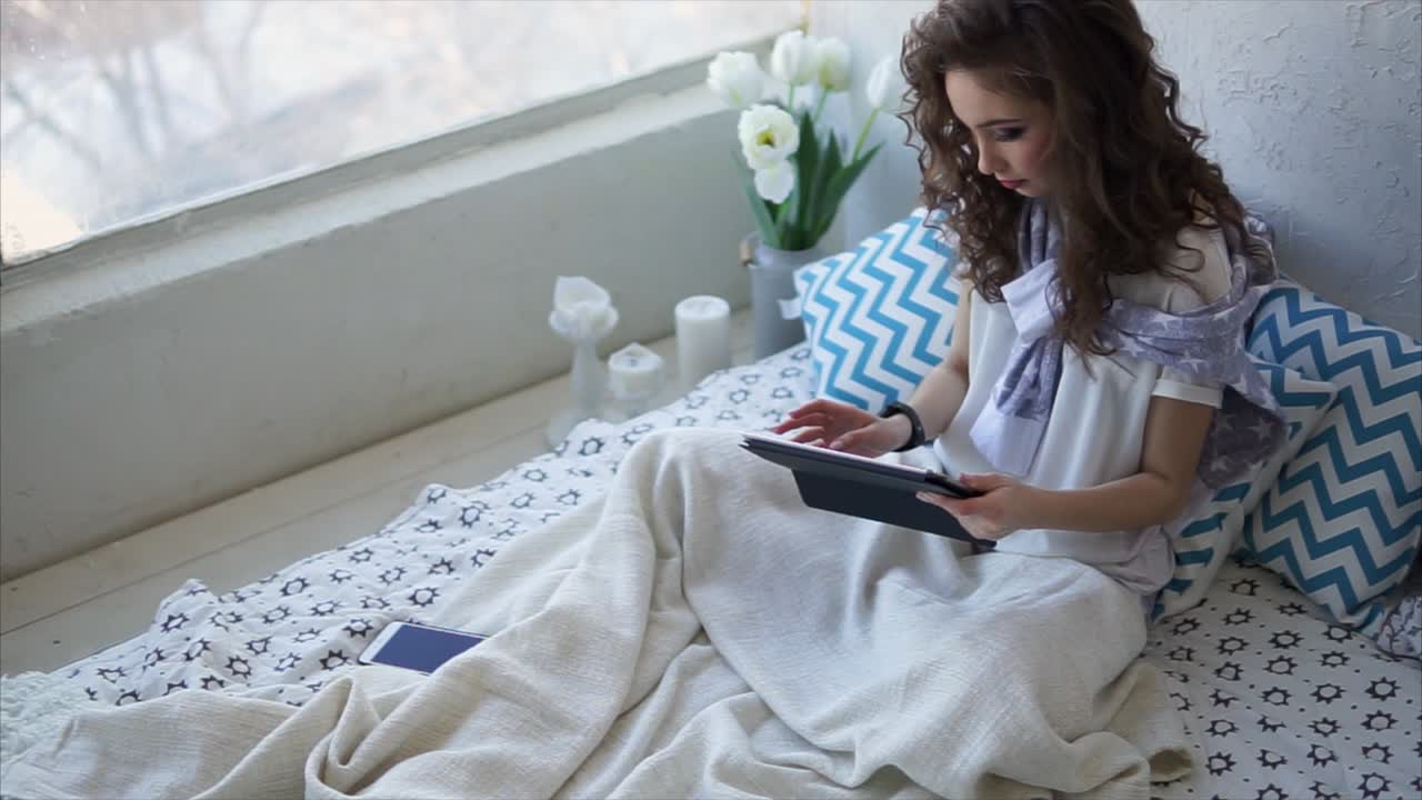 mujer relajándose en la cama con la tableta