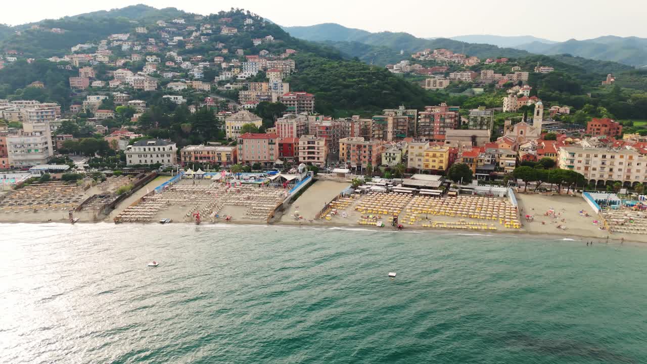 Colorful buildings along the Ligurian coast with a bustling beach and clear blue sea