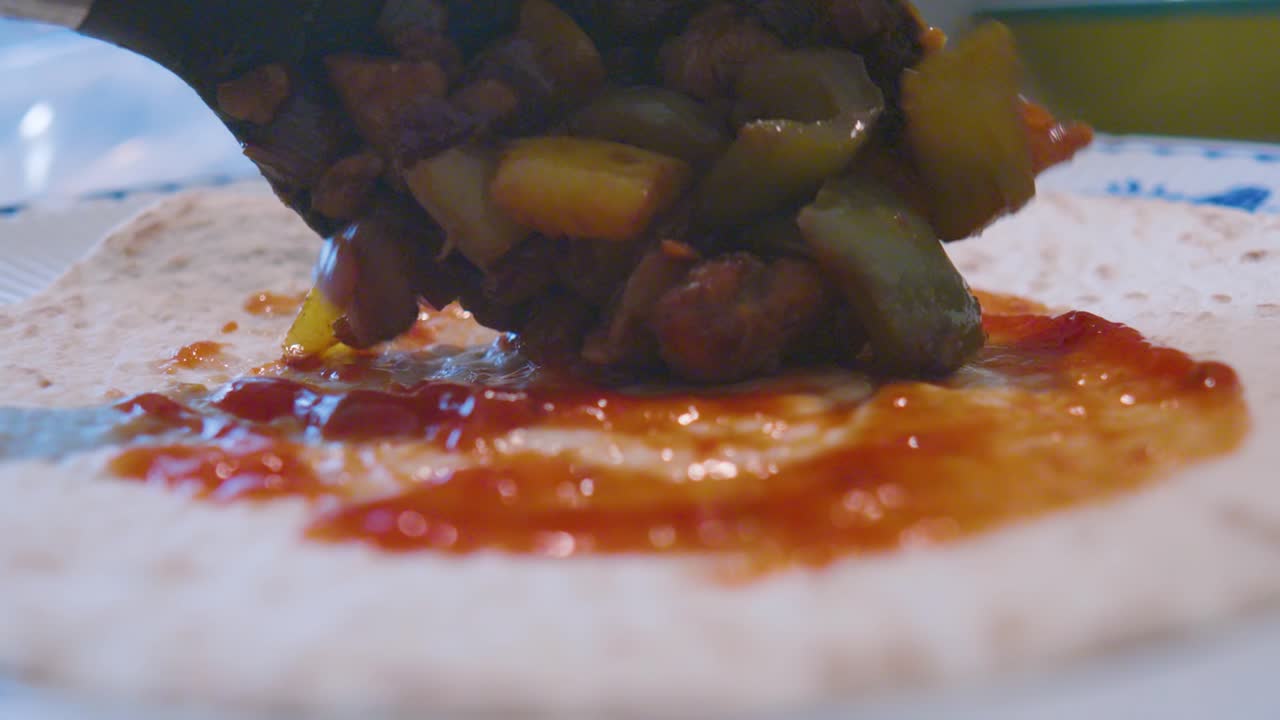 Salsa Sauce Spread Over Tortilla with Spicy Fajitas Mix Gently Lowered Down Ready to Wrap and Eat.