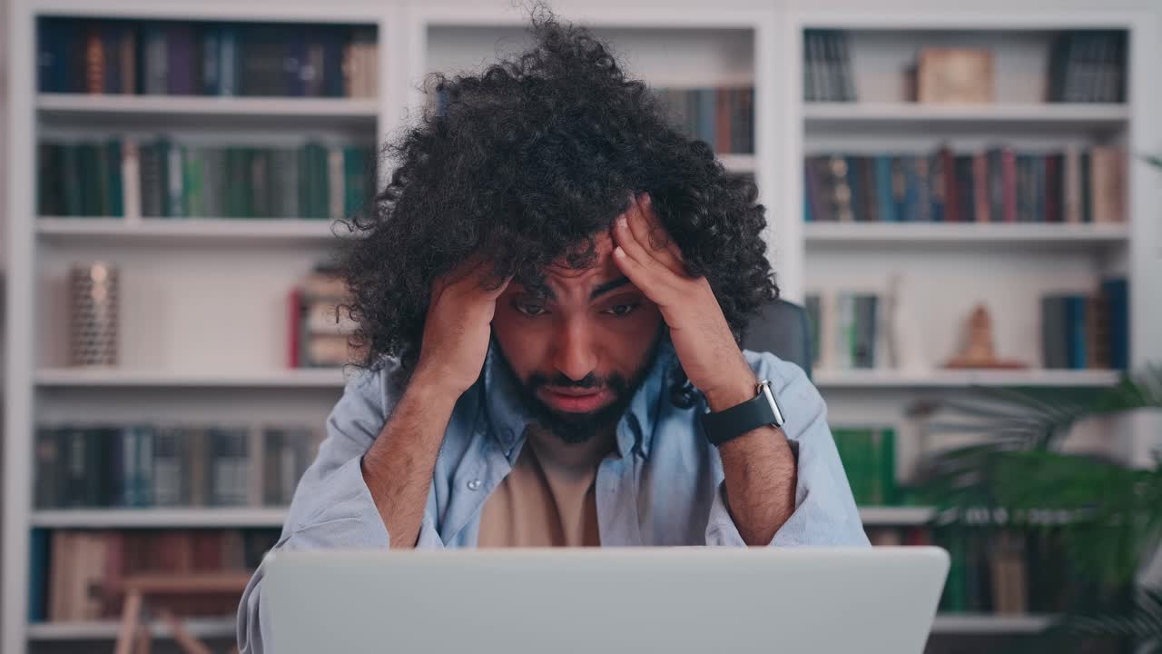 Tired young arabian man grabs head of temples due to fatigue overtime working