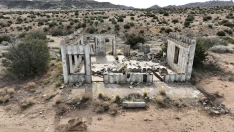 edificios abandonados estructuras de hormigón destruidas por el cártel en el alto desierto del sur de california en un día nublado con un estado de ánimo apocalíptico pan de camiones aéreos 60fps