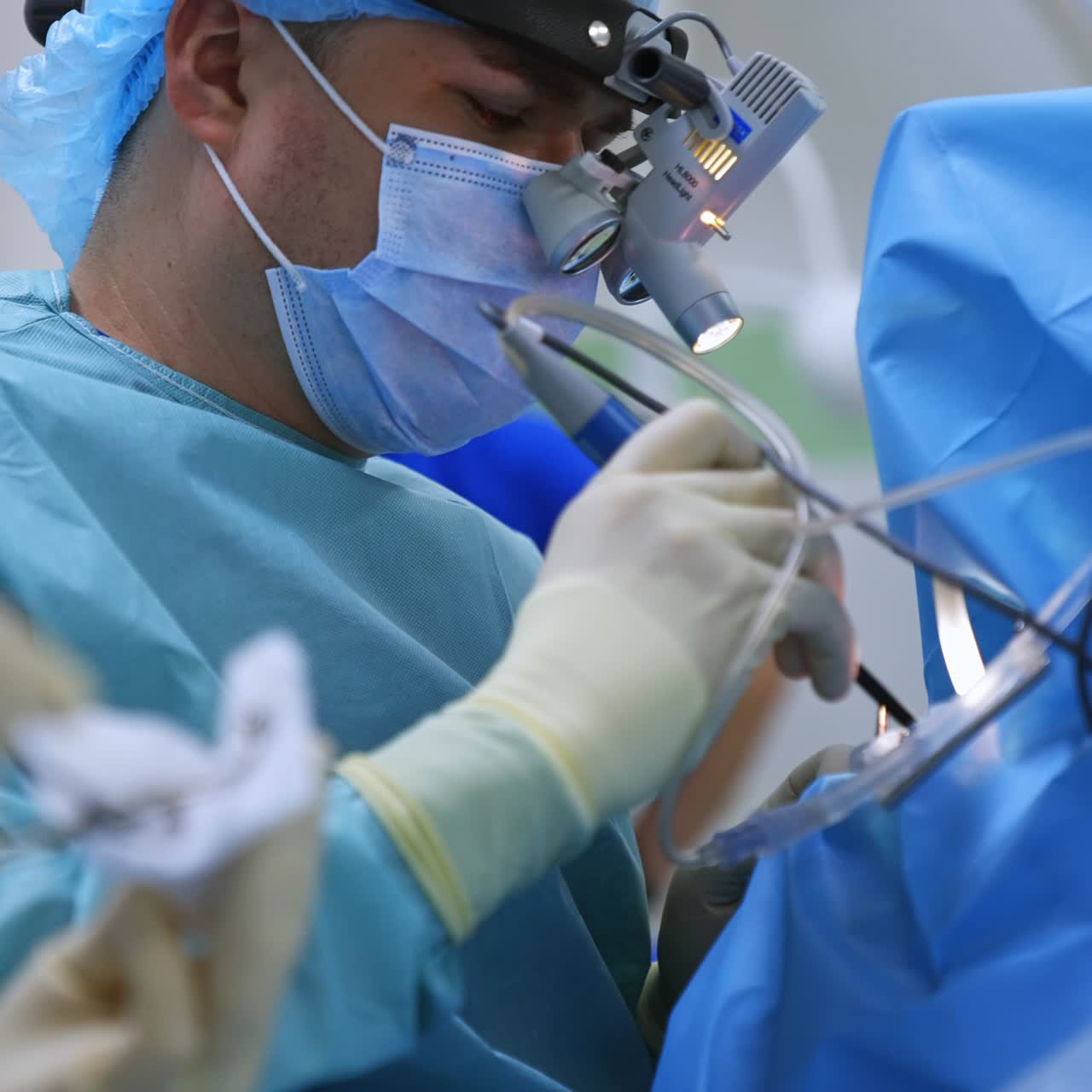 Vertical screen: Doctor using innovative equipment performing nasal surgery. Nurse's hands in latex gloves cleaning the instruments