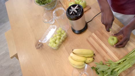 midsection of african american man preparing healthy smoothie in kitchen at home, slow motion