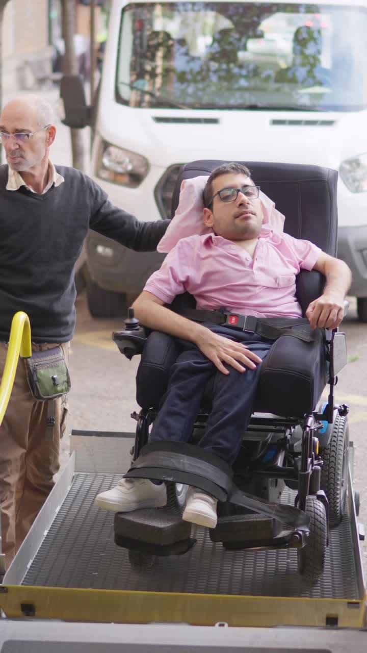 Uomo su sedia a rotelle che viene abbassato da un ascensore da un furgone accessibile