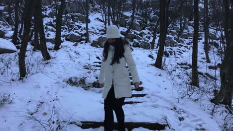 Woman-climbing-down-snowy-stairs-in-the-mountain,-Extremely-wide-shot