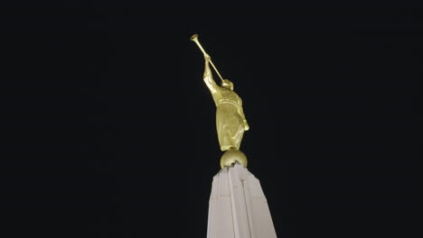 golden statue of the angel moroni with trumpet in hand on top of lds church mormon temple at night in gilbert, arizona