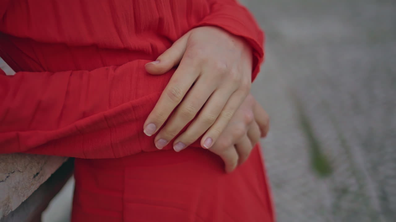 Red dress woman hands resting city square closeup. Young lady leaning fountain