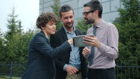 business team discussing on tablet outside office building