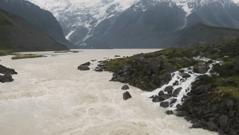 un río de montaña inundado por la nieve derretida con agua turbulenta corriendo sobre las rocas