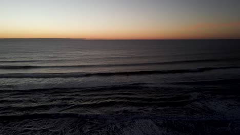 aerial view of the sunset with the reflection of daylight and the sea waves in the background