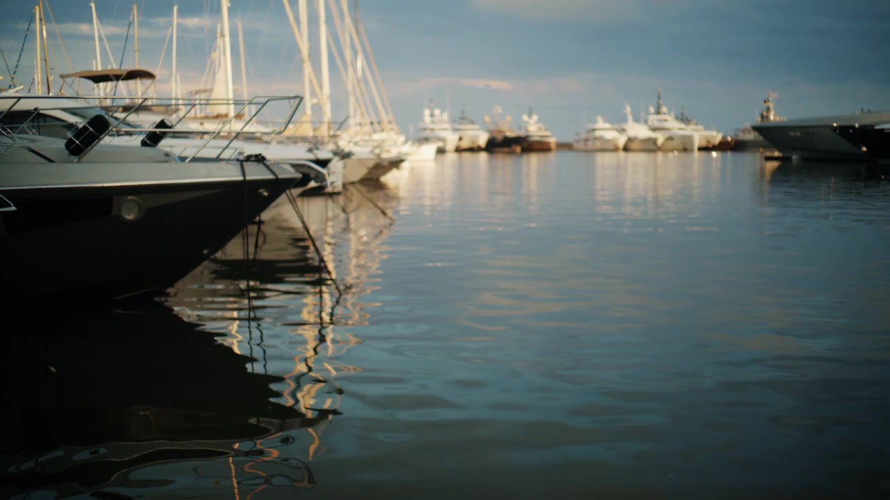 Filmische Untersicht von Yachten und Segelbooten, die sich im ruhigen Wasser des Port Vauban, Antibes, während des sanften goldenen Lichts an der Französischen Riviera spiegeln.