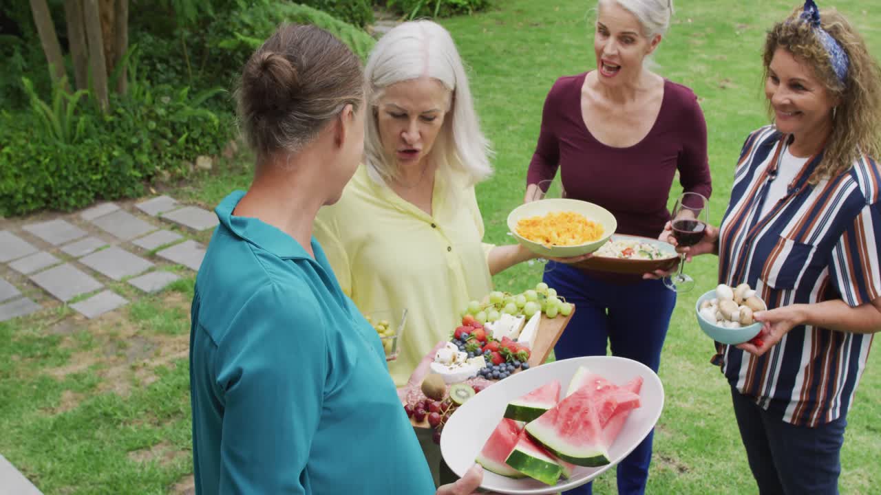 animación de felices y diversas amigas y amigos mayores preparando el almuerzo en el jardín