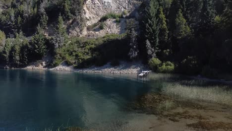 Toma-Aérea-Avanzando-De-Una-Playa-En-El-Lago-Glaciar-Alpino-Rodeado-De-Bosque-En-Bariloche,-Colonia-Suiza,-Patagonia-Argentina