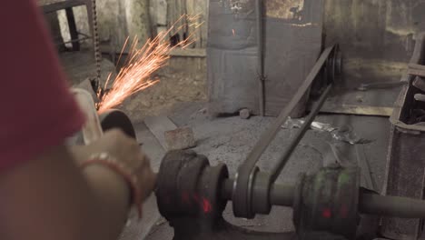 knife sharpening wheel grinding with flame sparks at dingy workshop