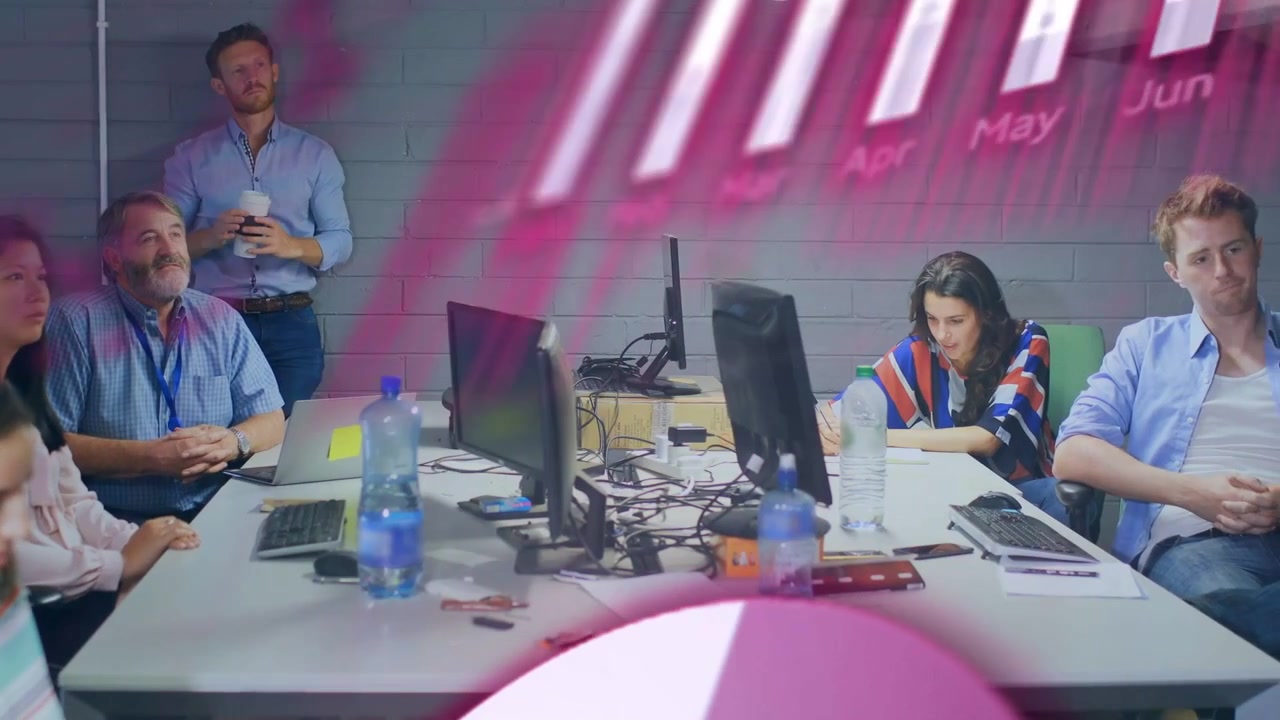 Gráficos animados de color rosa barriendo el primer plano, revelando a un equipo de negocios analizando datos y tomando notas.