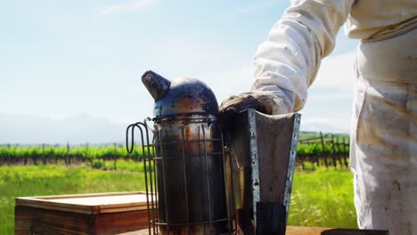 Close-up-of-beekeeper-keeping-bee-smoker-on-honeycomb-box