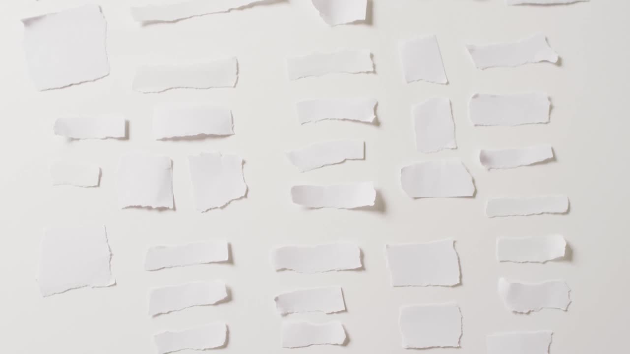 video de un primer plano de varias piezas de papel rasgadas sobre un fondo blanco