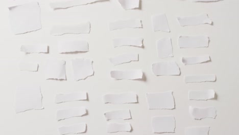 video of close up of multiple torn pieces of paper on white background