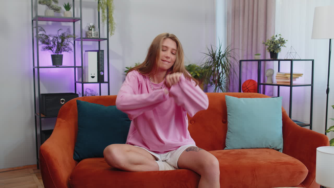 트렌디하고 즐거운 긍정적인 여성이 춤을 추고 리 ⁇ 에 따라 움직이며 현대 가정에서  ⁇  댄스 제스처를 만 ⁇ 니다.