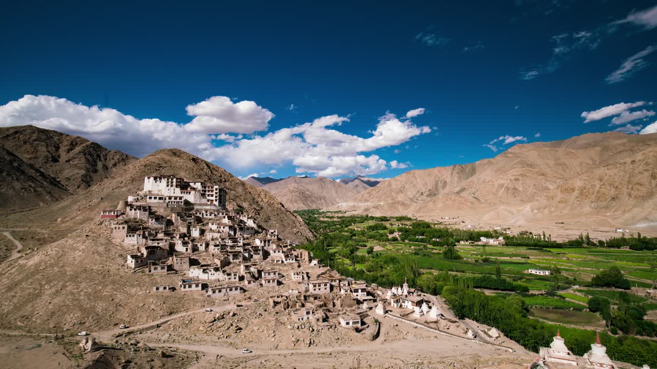 Chemdey Gompa med udsigt over Himalaya-dalen med frodig grøn vegetation og strålende blå himmel med bløde skyformationer