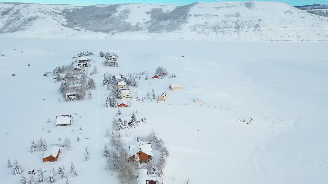 An eagle-eye drone shot of the Snow-Covered Mountains and houses in villages in the Perfect Winter Escape in Park City, Utah