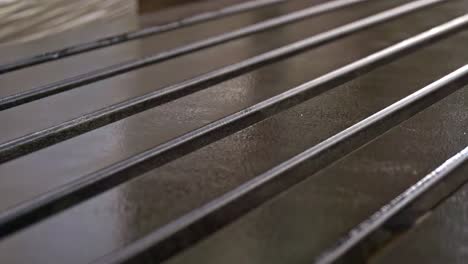 a close-up shot shows the process of a row of wooden planks being spray-painted with a wet, glossy finish, highlighting the painting and varnishing process in a furniture factory