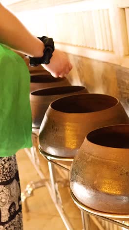 person donating coins into temple bowls