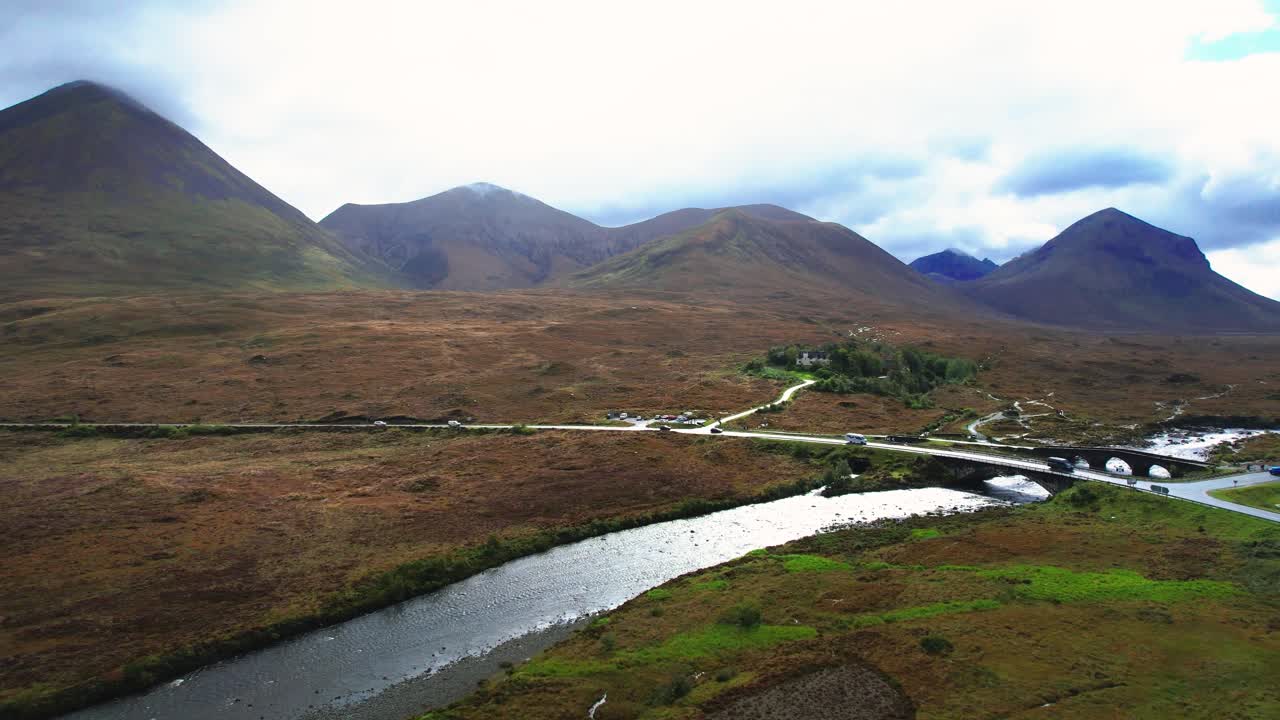 Auto che guidano verso l'isola di Skye nelle Highlands scozzesi, attraversando il ponte di Sligachan con le montagne