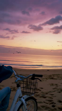 young boy on bicycle watching a vibrant sunset at the beach