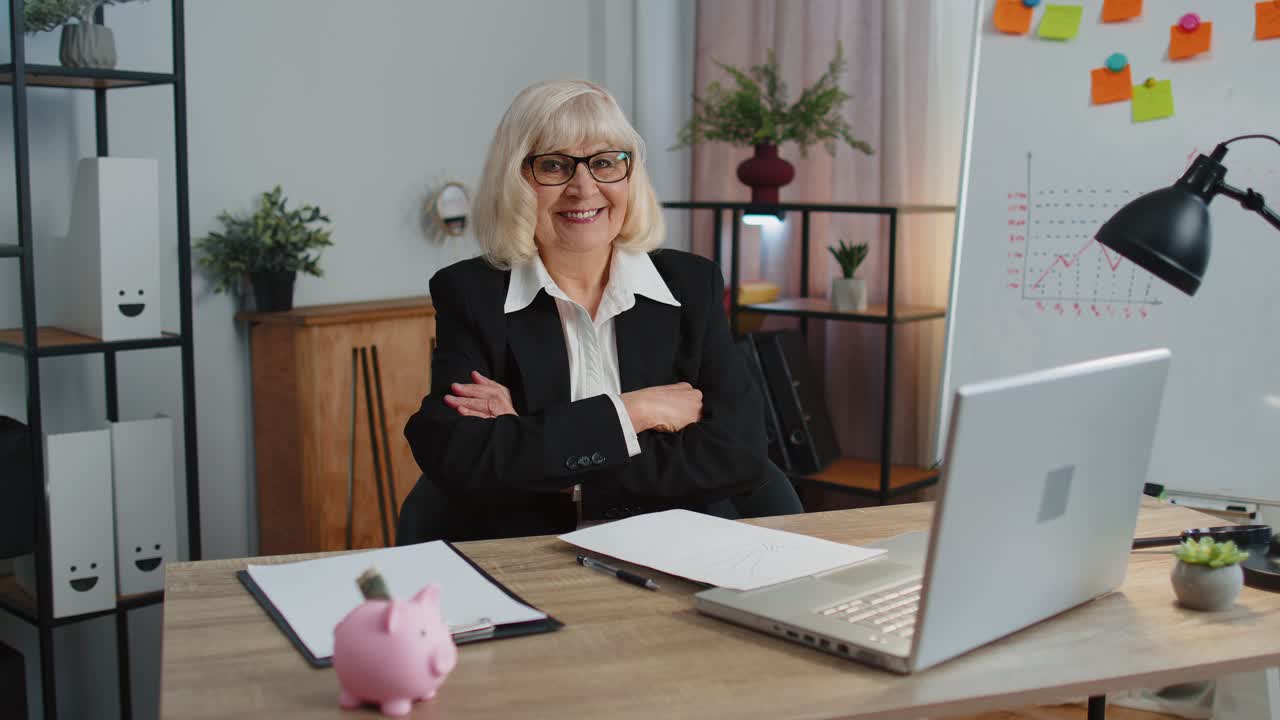 Senior business woman raises thumbs up agrees approve likes good news using laptop at home office
