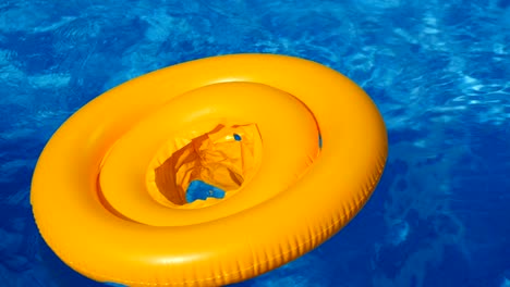 floating ring on blue water of swimpool with waves reflecting in the summer sun